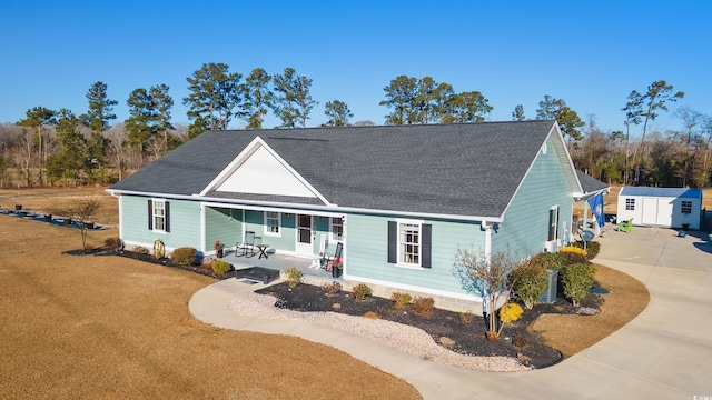 view of front of house with a porch, a front lawn, driveway, and an outdoor structure