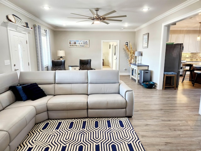 living area featuring light wood finished floors, baseboards, ornamental molding, and a ceiling fan