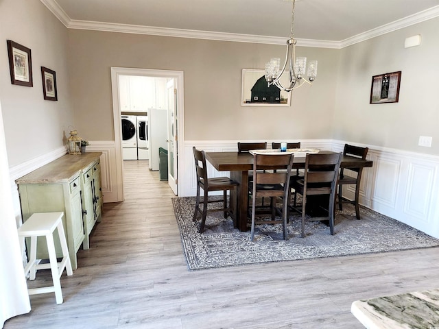 dining area with light wood-type flooring, wainscoting, crown molding, and washing machine and clothes dryer