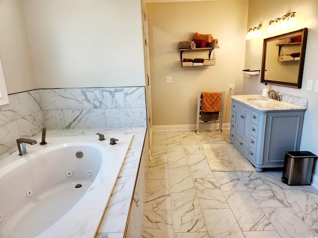 bathroom with marble finish floor, a tub with jets, vanity, and baseboards