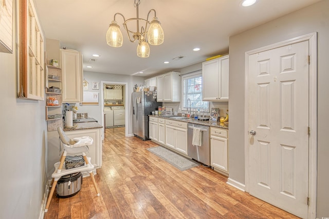 kitchen featuring appliances with stainless steel finishes, pendant lighting, washer and clothes dryer, and white cabinets