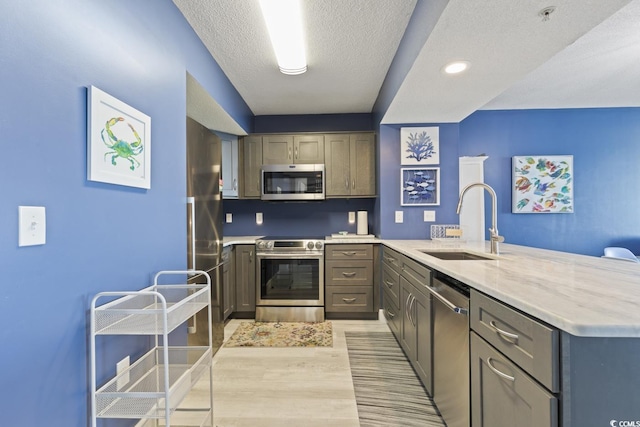 kitchen with gray cabinets, sink, light stone countertops, appliances with stainless steel finishes, and a textured ceiling