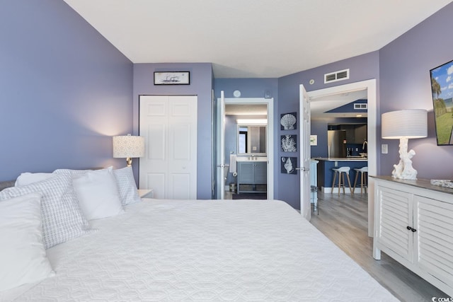 bedroom with a closet, hardwood / wood-style flooring, and stainless steel fridge