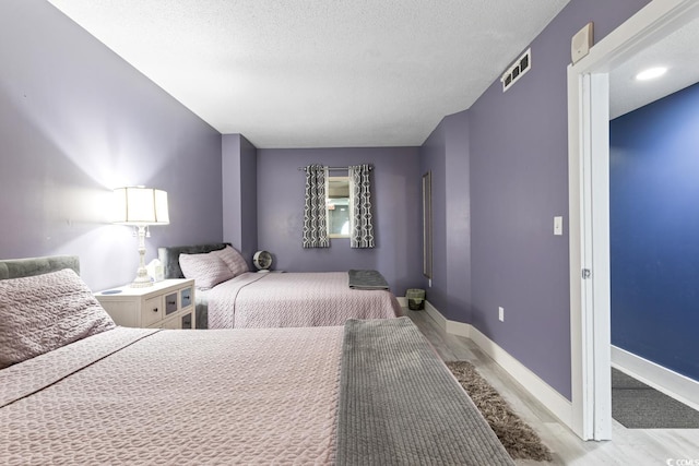 bedroom with light hardwood / wood-style floors and a textured ceiling