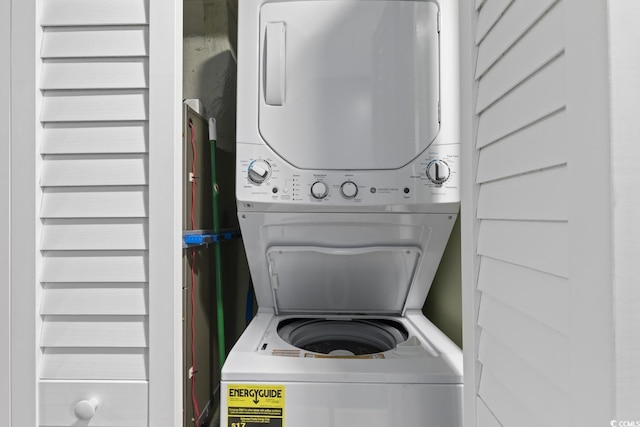 washroom featuring stacked washer / drying machine and wood walls