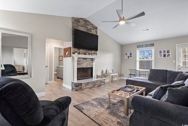 living room featuring light hardwood / wood-style floors, a large fireplace, ceiling fan, and vaulted ceiling