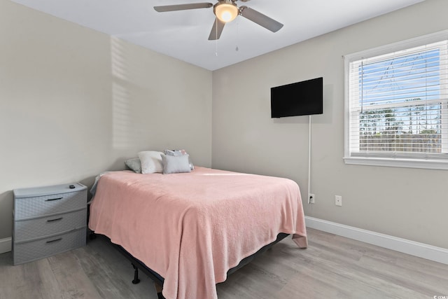 bedroom featuring ceiling fan, multiple windows, and light hardwood / wood-style flooring