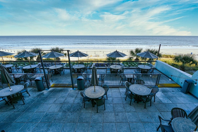 view of patio / terrace with a water view and a beach view