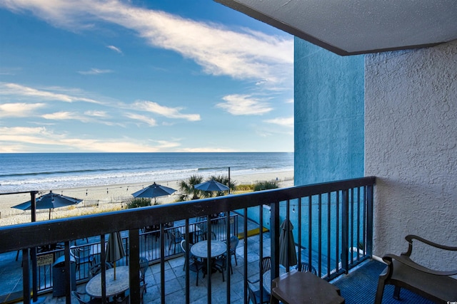 balcony featuring a beach view, grilling area, and a water view