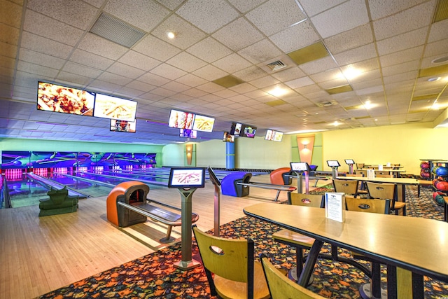 recreation room featuring a drop ceiling, bowling, and hardwood / wood-style floors