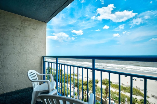 balcony with a water view and a view of the beach