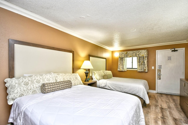 bedroom featuring hardwood / wood-style floors, crown molding, and a textured ceiling