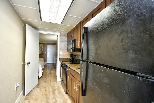 kitchen featuring black appliances, dark stone counters, and light hardwood / wood-style flooring