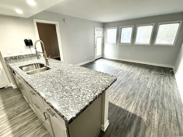 kitchen featuring a center island, sink, dark wood-type flooring, white cabinets, and light stone counters