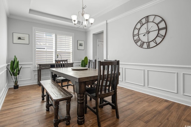 dining area with a raised ceiling, crown molding, an inviting chandelier, and dark hardwood / wood-style flooring