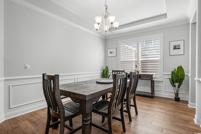 dining space with dark hardwood / wood-style flooring, a tray ceiling, ornamental molding, and a chandelier