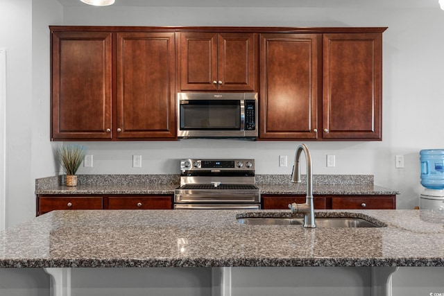 kitchen with sink, stainless steel appliances, and dark stone counters