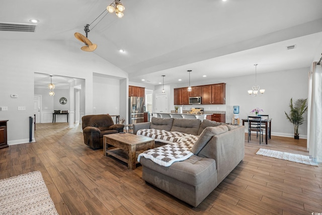 living room featuring lofted ceiling, wood-type flooring, and a notable chandelier