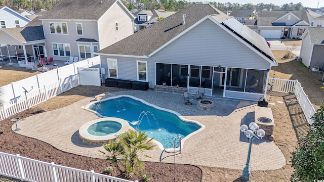 view of swimming pool featuring an in ground hot tub, an outdoor fire pit, a patio area, and a sunroom