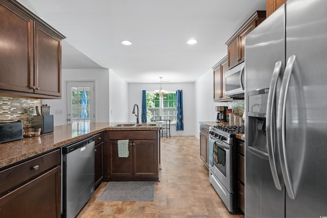 kitchen with appliances with stainless steel finishes, pendant lighting, sink, backsplash, and dark stone counters