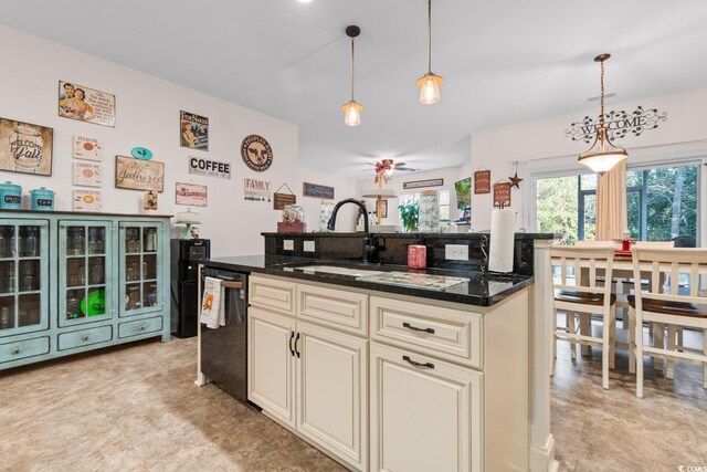 kitchen with hanging light fixtures, cream cabinetry, dark stone counters, and sink