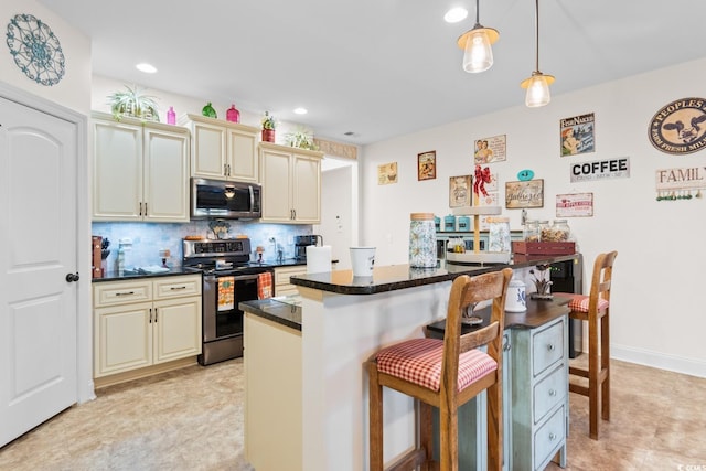 kitchen with hanging light fixtures, a breakfast bar, appliances with stainless steel finishes, and cream cabinets