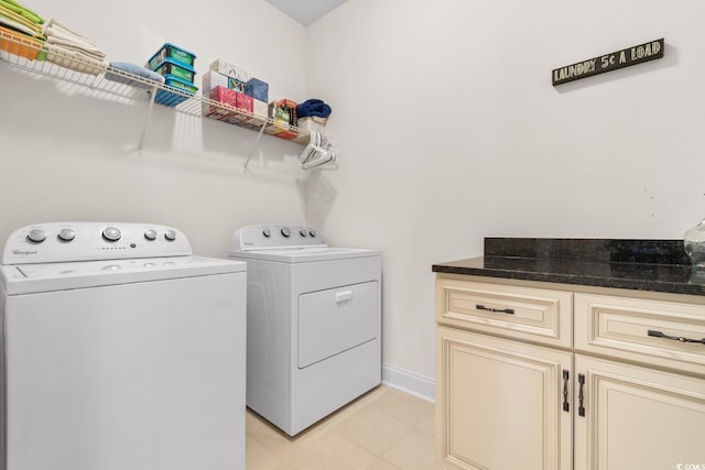 clothes washing area with washing machine and dryer, cabinets, and light tile patterned flooring