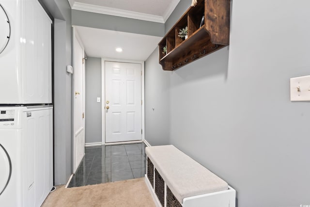 mudroom featuring dark tile patterned floors, stacked washer and clothes dryer, and crown molding