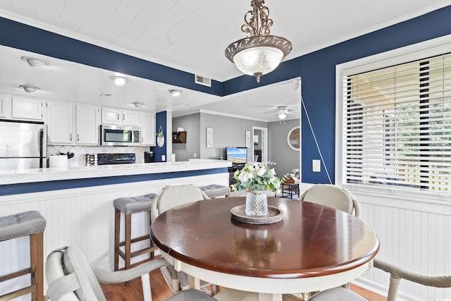 dining area with light wood-type flooring, ceiling fan, and crown molding