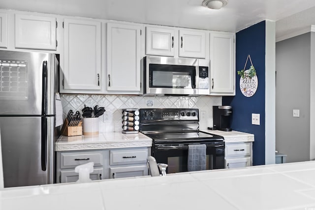 kitchen with white cabinets, backsplash, appliances with stainless steel finishes, and crown molding