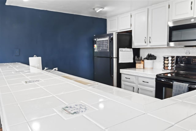 kitchen featuring black appliances, tasteful backsplash, tile countertops, and white cabinetry