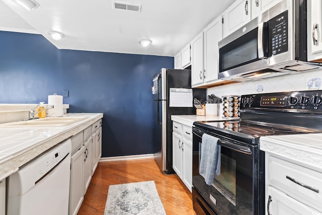 kitchen with white cabinetry, appliances with stainless steel finishes, tasteful backsplash, light hardwood / wood-style flooring, and sink