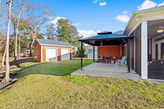 view of yard with a garage, a gazebo, a sunroom, an outdoor structure, and a patio