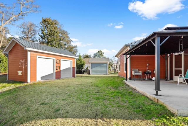 view of yard featuring an outbuilding, a garage, and a patio area