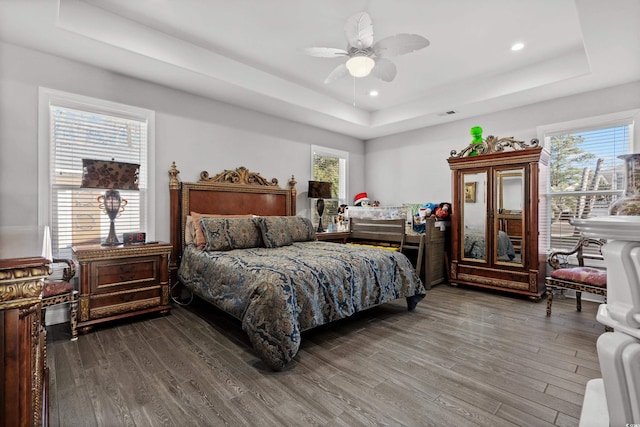 bedroom with hardwood / wood-style floors, a tray ceiling, and ceiling fan