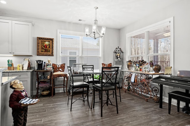 dining space featuring dark hardwood / wood-style floors and an inviting chandelier