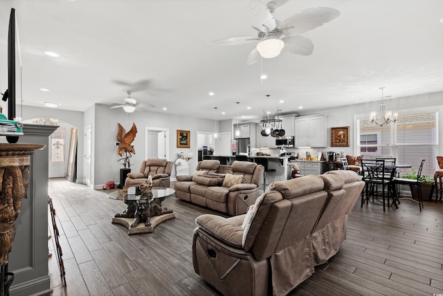 living room featuring ceiling fan with notable chandelier and hardwood / wood-style floors