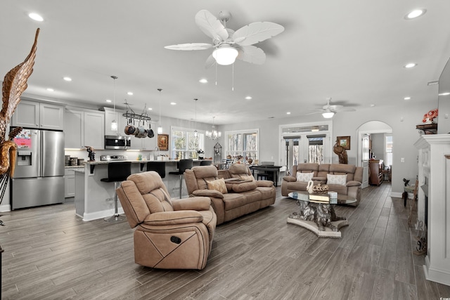 living room featuring ceiling fan with notable chandelier and light hardwood / wood-style flooring