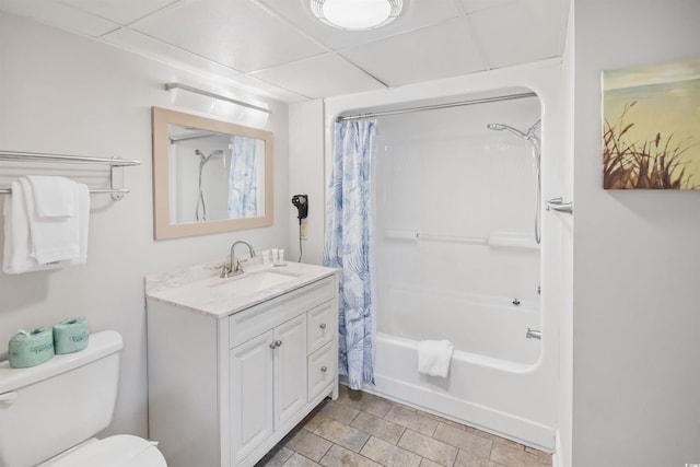 full bathroom featuring toilet, a drop ceiling, vanity, and shower / bath combo with shower curtain