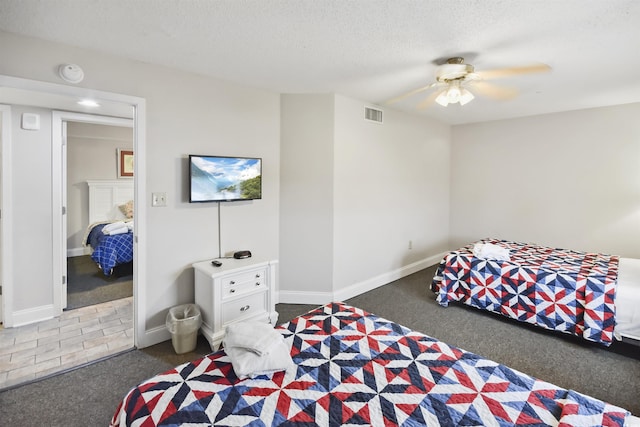 bedroom featuring ceiling fan, a textured ceiling, and dark colored carpet