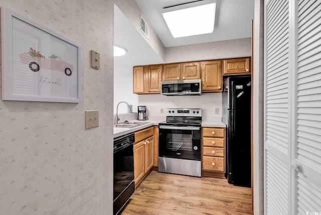 kitchen with sink, light hardwood / wood-style flooring, and black appliances