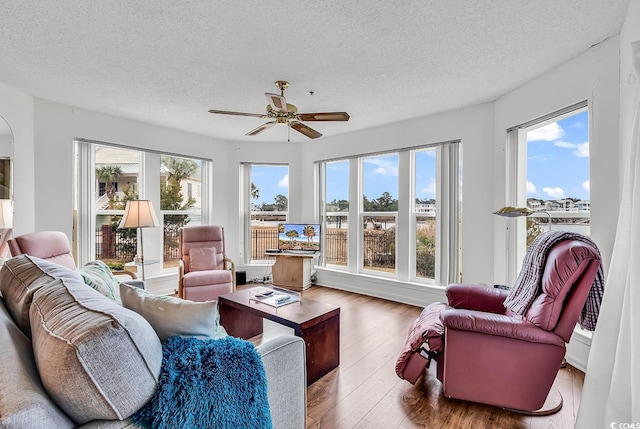 living room with hardwood / wood-style flooring, ceiling fan, and a textured ceiling