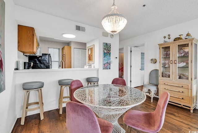 4560 Greenbriar Dr Unit 102-B, Little River, SC 29566 - dining room featuring dark wood-style flooring, visible vents, a notable chandelier, and a textured ceiling