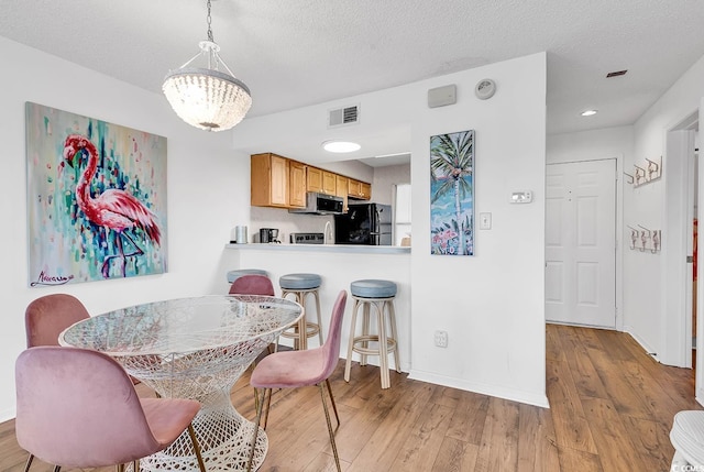 dining space featuring a textured ceiling and light hardwood / wood-style floors