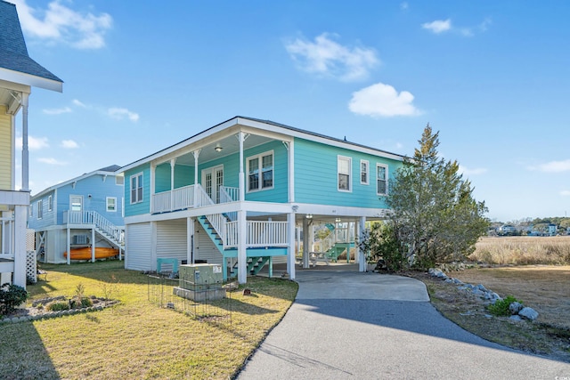 coastal inspired home featuring cooling unit, a carport, a porch, and a front yard