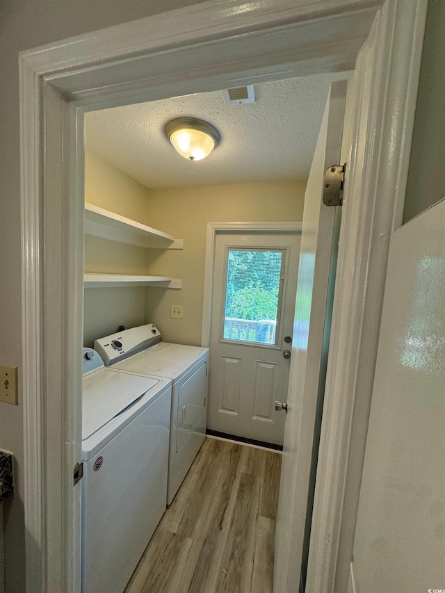 washroom featuring washer and clothes dryer, a textured ceiling, and light wood-type flooring