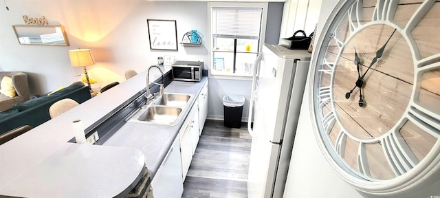 kitchen featuring a sink, white cabinetry, light countertops, dark wood-style floors, and stainless steel microwave