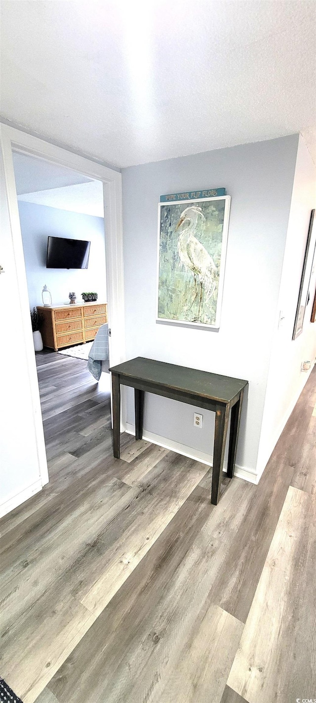 interior space with a textured ceiling, wood finished floors, and baseboards