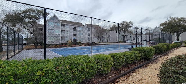 view of tennis court with a residential view and fence