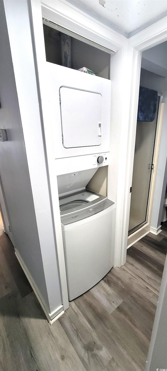 laundry room featuring stacked washer and dryer and wood finished floors